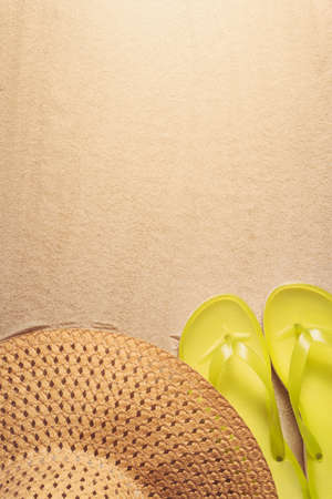Summer holiday background with yellow flip flops and straw hat on sandy beach, top view with copy spaceの写真素材