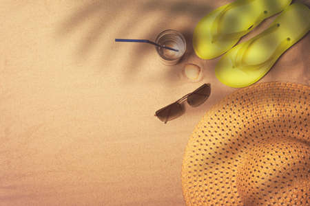 Flip flops, straw hat and sunglasses on a sandy background, top viewの写真素材