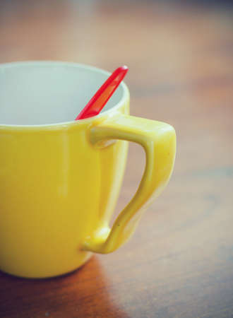 Yellow cup with red spoon on the table in vintage styleの写真素材
