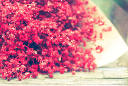 Red bouquet on wooden background in vintage toneの写真素材