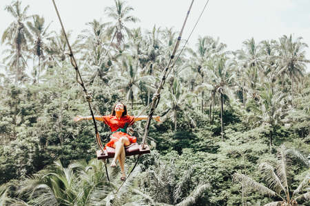Young pretty Asian woman is swinging on the cliff of the jungle in Ubud, Bali.の写真素材