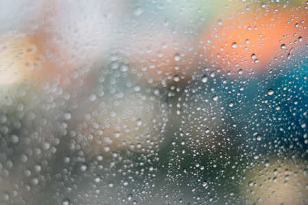 Blurred rainy window with red bokeh lightの写真素材