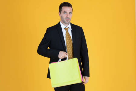 Portrait of businessman with shopping bags on yellow  background.の写真素材