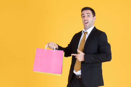 Portrait of businessman with shopping bags on yellow  background.の写真素材