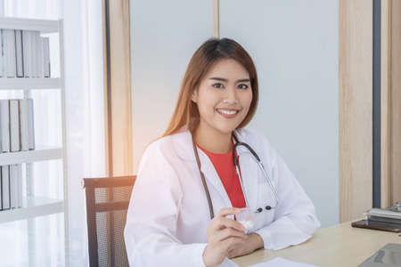 Young Asian doctor working on her desk, holding medicine, hospital and healthcare concept.の写真素材