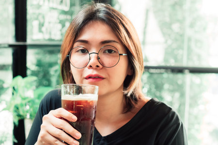 A pretty Asian woman is holding iced coffee with blurred background.の写真素材