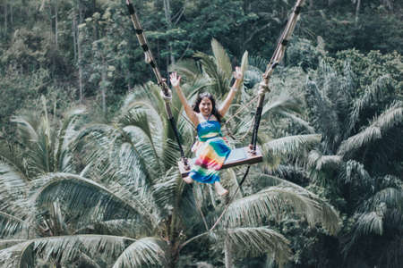 Young pretty Asian woman is swinging on the cliff of the jungle in Ubud, Bali.の写真素材
