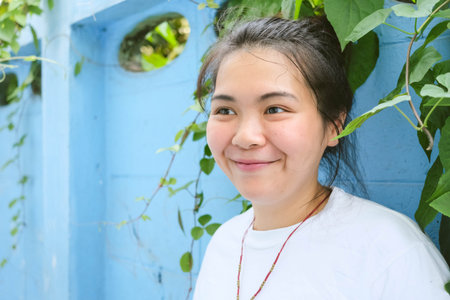 Close up of young pretty Asian woman in a white T-shirt with blue wall background.の写真素材