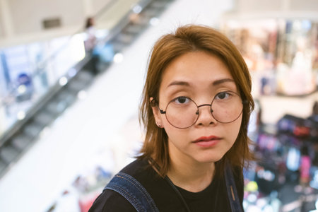 Closeup of young Asian woman with blur shopping mall background.
