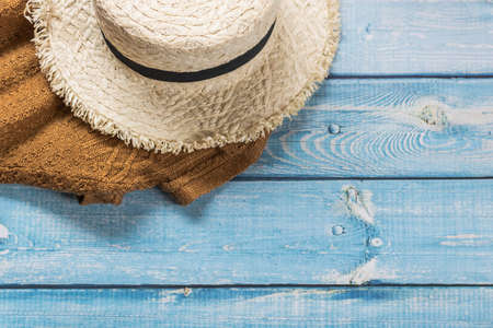 A straw hat with brown knitting shirt on light blue wooden background, beach and Summer concept.の写真素材
