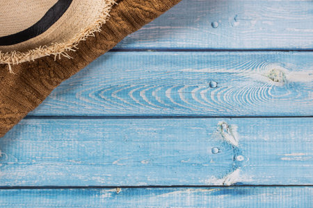 A straw hat with brown knitting shirt on light blue wooden background, beach and Summer concept.の写真素材