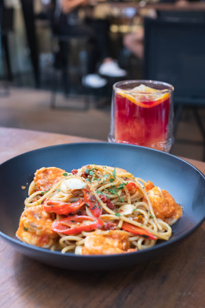 Close-up of spaghetti with shrimp served with a glass of fruit drink in the restaurant.の写真素材