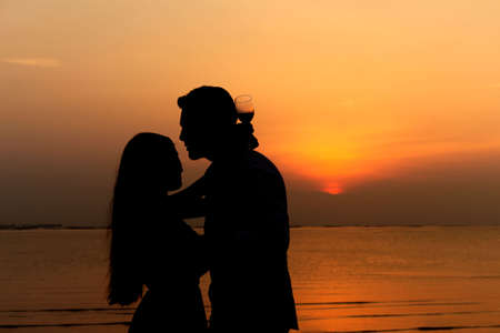 Front view of a body of a couple silhouette on the beach at sunset in summerの写真素材