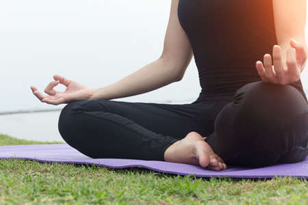 Close up hand. Woman do yoga outdoor.Woman exercising yoga at the sea background.concept of healthy life and natural balance between body and mental development.の写真素材