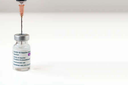London, UK - 08 Mar 2021: Close-up of Astra Zeneca Pharmaceuticals' coronavirus vaccine next to a syringe. Copy spaceのeditorial素材