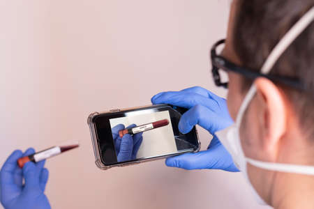 Doctor with mask and goggles wearing blue latex gloves. White background.の写真素材