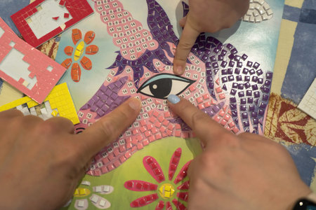 Close-up of a child's hands doing a puzzle with his mother. Concept of teaching and learning as a...