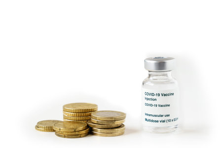 Coronavirus vaccine vial on top of a pile of coins on white background. Copy spaceの写真素材