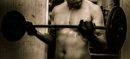 Young guy with muscular body with barbell over, dramaticの写真素材