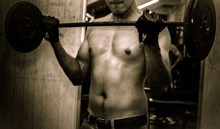 Young guy with muscular body with barbell over, dramaticの写真素材