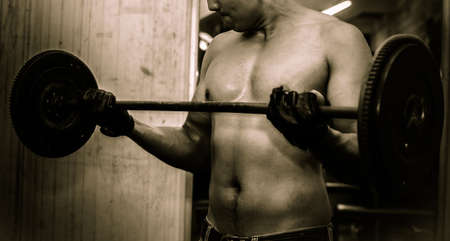 Young guy with muscular body with barbell over, dramaticの写真素材