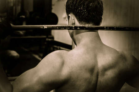 Young guy with muscular body with barbell over, dramaticの写真素材