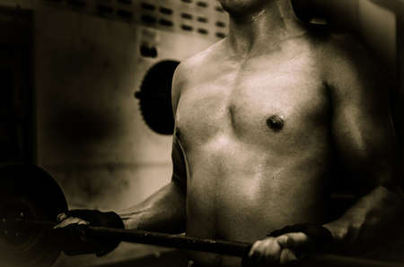 Young guy with muscular body with barbell over, dramaticの写真素材