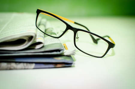 Stack of newspapers   glasses on table の写真素材