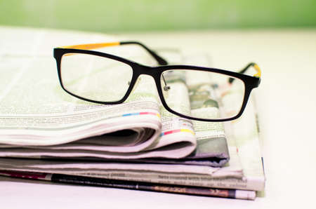Stack of newspapers   glasses on table の写真素材