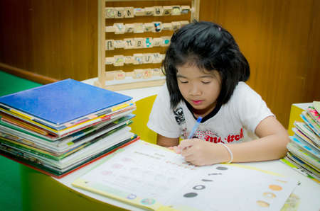 Schoolgirl doing her homework at her desk in the house.の写真素材