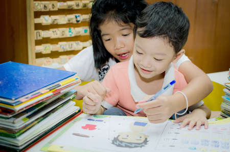 Sister helping brother to writing homeworkの写真素材