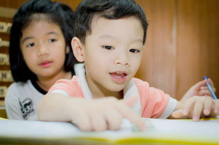 Sister helping brother to writing homeworkの写真素材