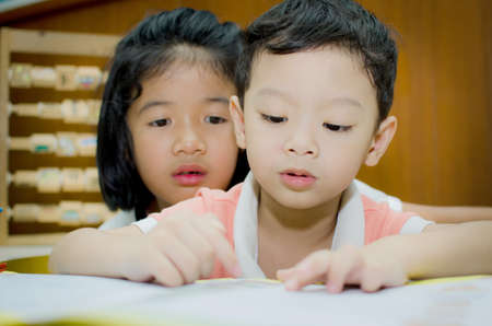 Sister helping brother to writing homeworkの写真素材