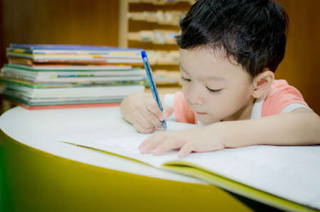 Schoolboy doing his homework at his desk in the house.の写真素材