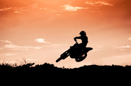 Status of silhouate motocross jumping over the amber light of sunset background.の写真素材