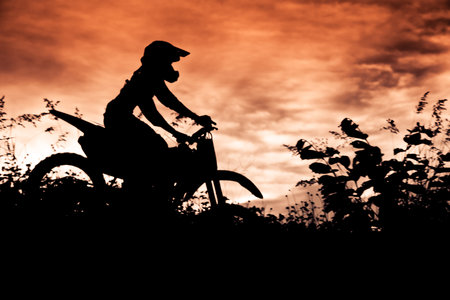 Status of silhouate motocross jumping over the amber light of sunset background.の写真素材