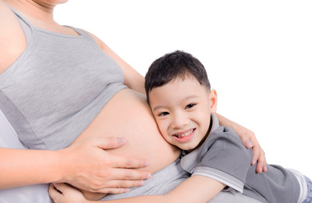 Boy loving her pregnant mother and hugging her belly.