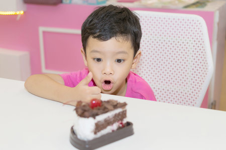 Little cute boy looking at a cake on the table.の写真素材