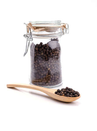 Black pepper in wooden spoon on white background.の写真素材