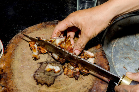 Man in the kitchen cooking roast pork: cutting meat.の写真素材