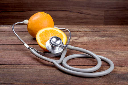 Orange with stethoscope on wooden tableの写真素材