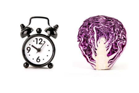 Alarm clock and red cabbage isolated on white background