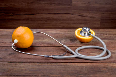Orange with stethoscope on wooden tableの写真素材