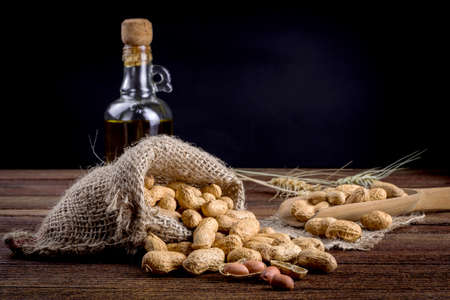 Peanuts in sack and spoon on dark wooden backgroundの写真素材