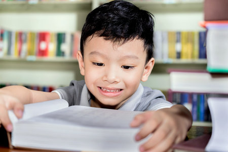 young asian boy with book in Library.