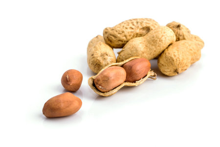 Dried peanuts in closeup on white background.