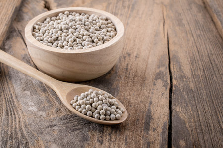 Pepper in a bowl on wooden background.