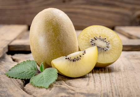 Whole and cut golden kiwifruit on wooden cutting boardの写真素材
