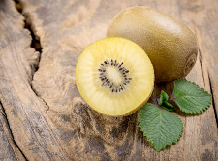 Whole and cut golden kiwifruit on wooden cutting boardの写真素材