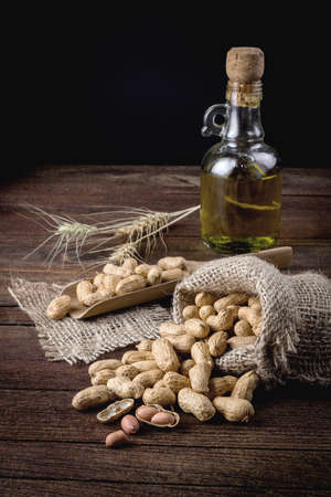 Peanuts in sack and spoon on dark wooden backgroundの写真素材